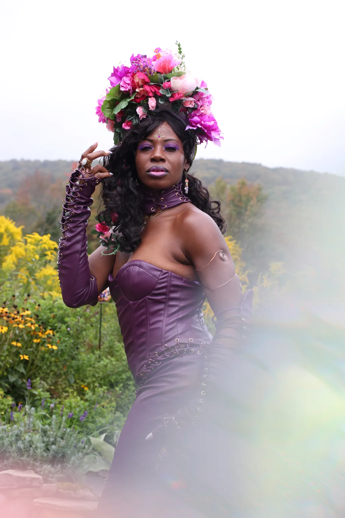 A woman in a purple leather corset gown wearing a crown of magenta and pink flowers