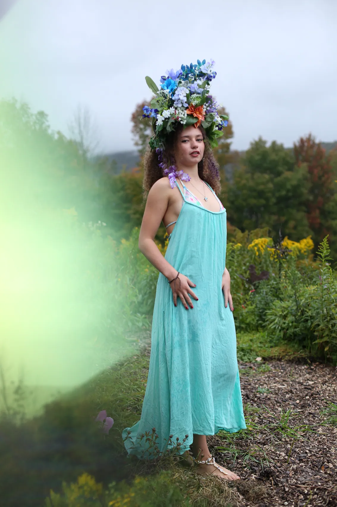 A young woman in a turquoise dress and a crown of blue delphinium