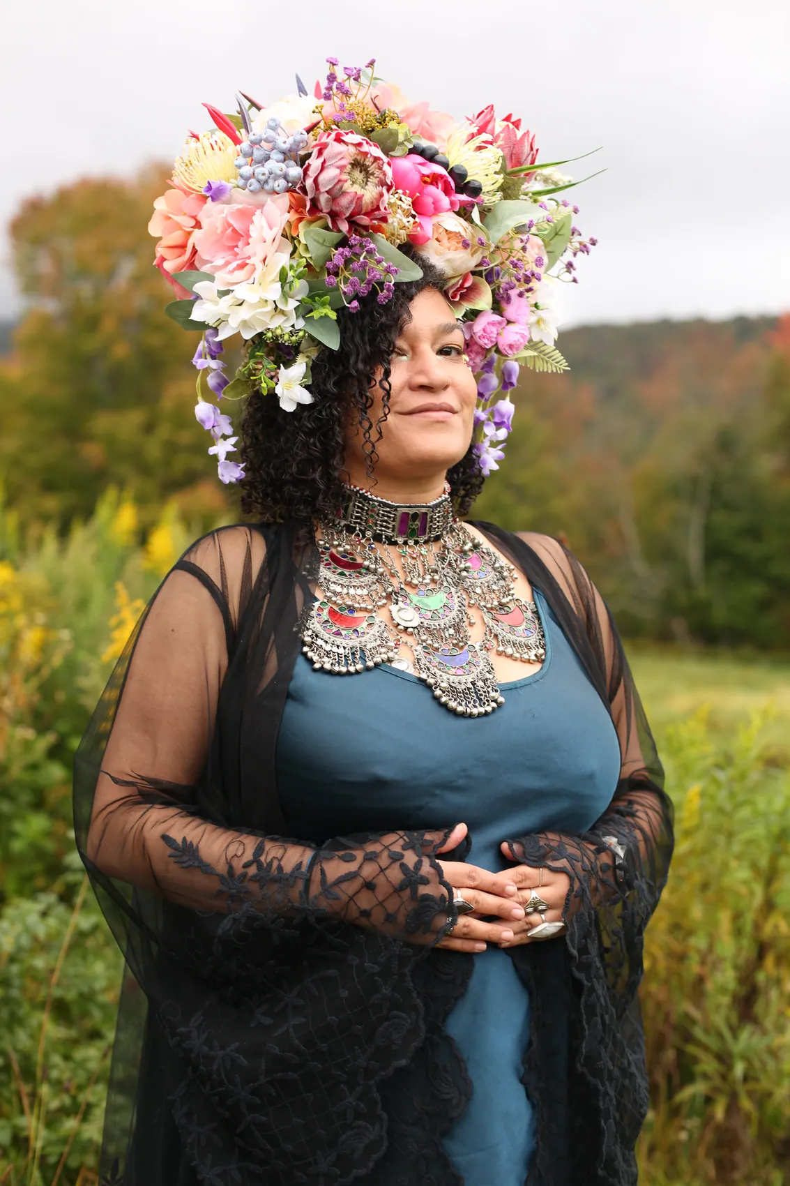 A woman in teal silk and black lace wearing a crown of pink protea and lilac blooms