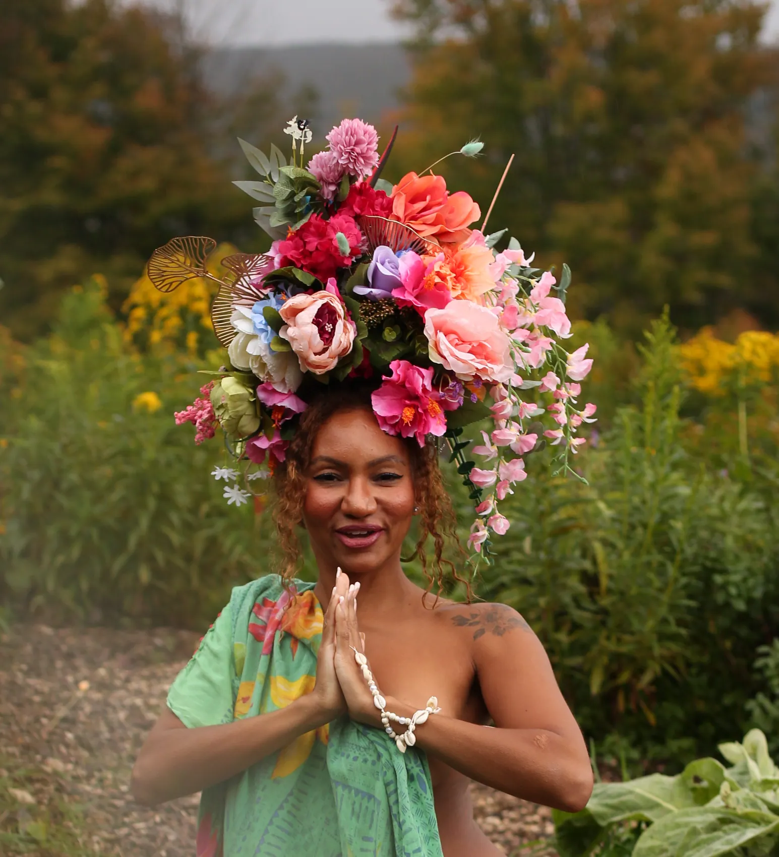 A woman with hands in prayer wearing a crown of peonies and sweet peas